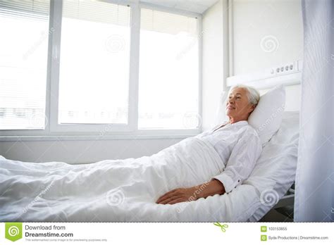 Smiling Senior Woman Lying On Bed At Hospital Ward Stock