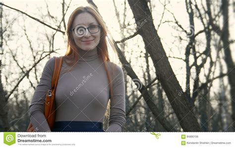 beautiful girl with red hair wearing glasses standing near brick wall