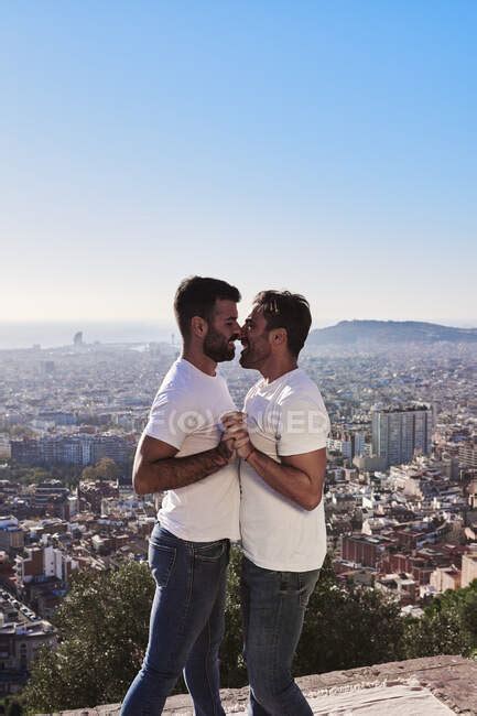 gay men embracing while standing against cityscape during sunny day
