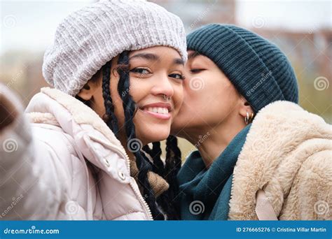Happy Dominican Lesbian Couple Taking A Selfie While Kissing On The