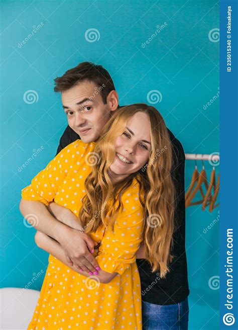 Young Man Hugs His Girlfriend From Behind Young Blonde Woman In Yellow