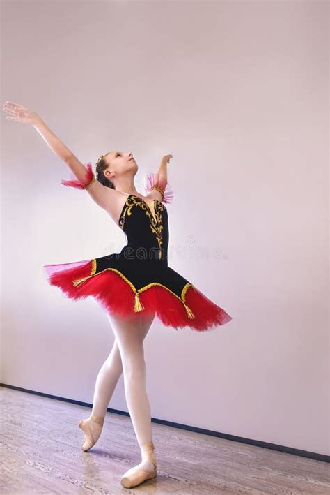 A Young Ballerina Stands Gracefully In Pointe Shoes On Her Toes In The