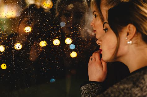 Lesbisches Paar Schaut Durch Fenster Bei Regen In Der Nacht Stockfoto