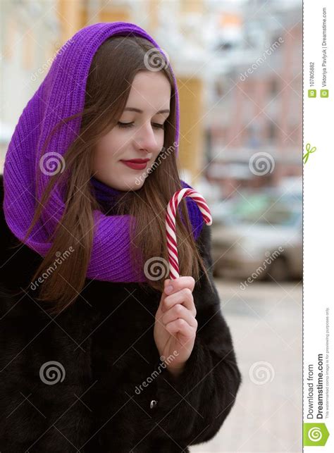 Adorable Young Woman Holding Caramel Candy Cane At The Street Stock