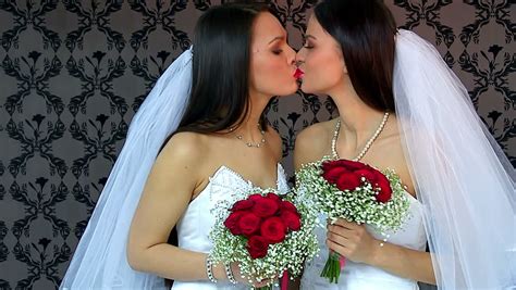 lesbian women with flowers bouquet kissing in erotic foreplay game and posing at camera
