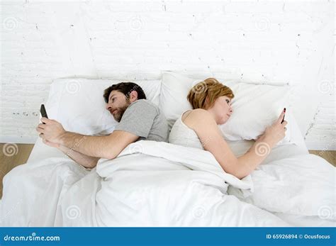 giovani coppie facendo uso del telefono cellulare a letto che si