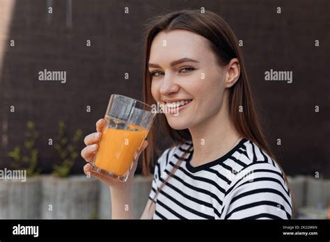 Woman With Pretty Smile Holding In Hand Glass Of Refreshing Orange