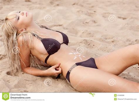 Woman Laying On Sand With Cream On Abdomen Royalty Free