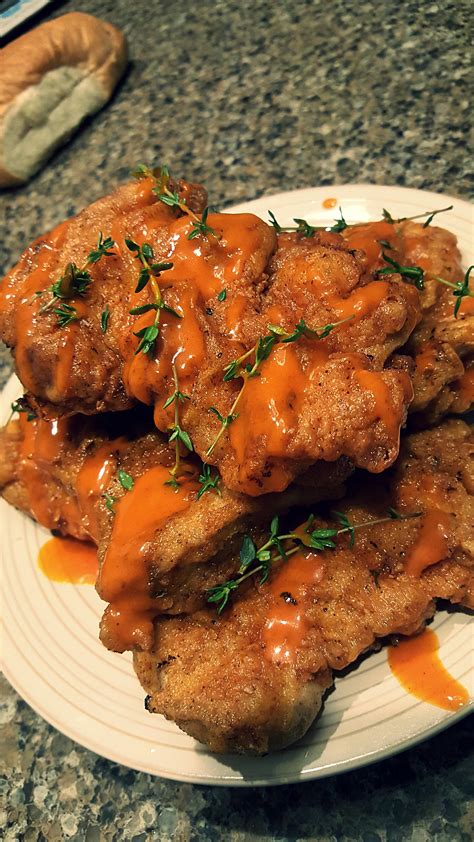deep fried chicken thighs with hot sauce and thyme sprigs