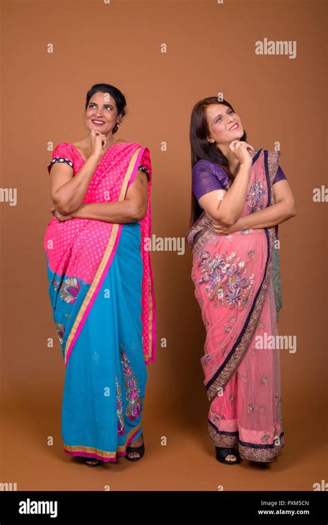 two happy mature indian women wearing traditional clothes and thinking