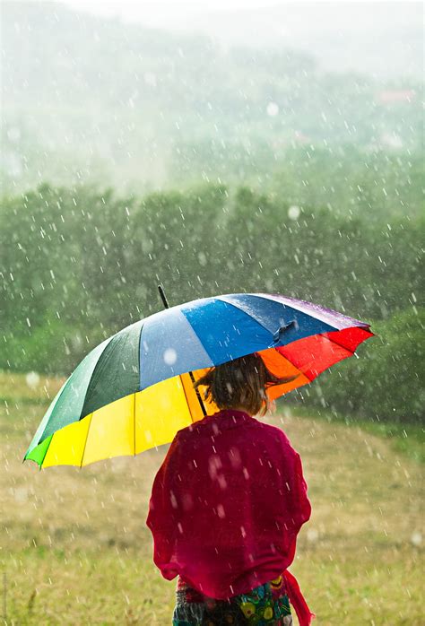 woman  colorful umbrella enjoying rain   meadow  stocksy