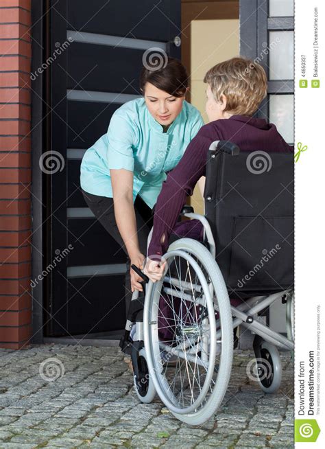 Caregiver Helping Disabled Woman Entering Home Stock Image