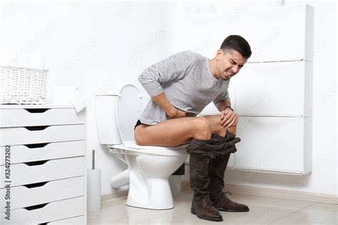 Man With Stomach Ache Sitting On Toilet Bowl In Bathroom Stock Foto