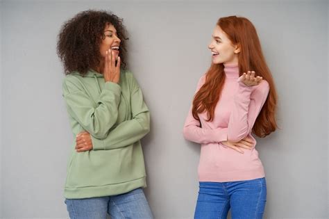 binnenfoto van vrij positieve jonge vriendinnen die vrolijk naar elkaar kijken met een aangename