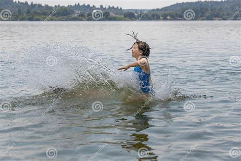 teenage girl in blue swimsuit bathes in calm cool lake water in hot