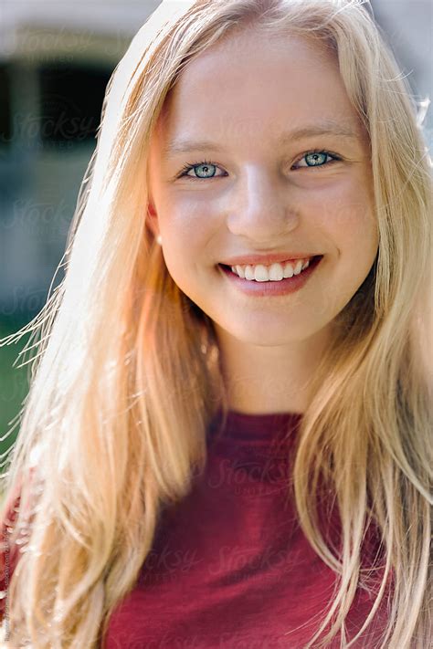 portrait of beautiful blond teen with blue eyes girl smiling by raymond forbes llc blond