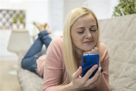 Blonde Girl Lie On The Couch And Look Into The Phone Stock Image