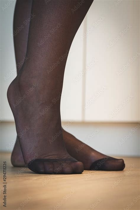 a close up portrait of the elegant feet of a girl in black pantyhose