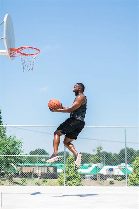 athletic african american man playing basketball  stocksy united