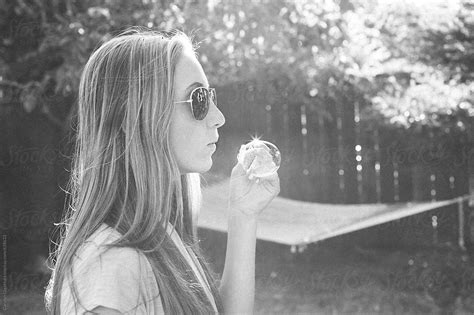 teenage girl with long blonde hair and sunglasses blowing bubbles del