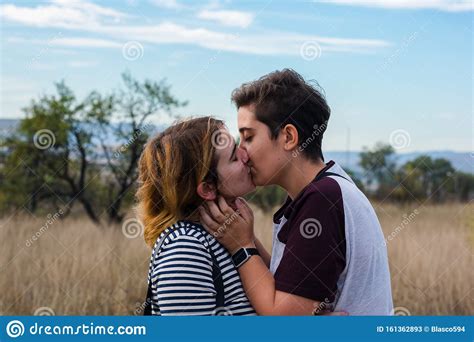 a lesbian couple are kissing in a meadow stock image