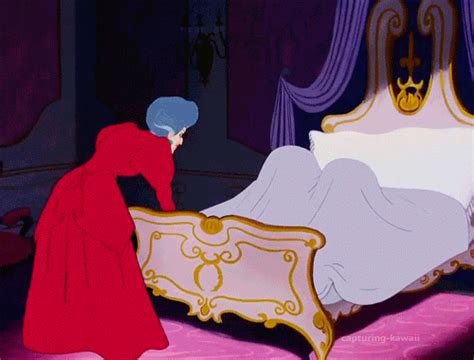 a woman in a red dress is looking at a bed with a golden headboard