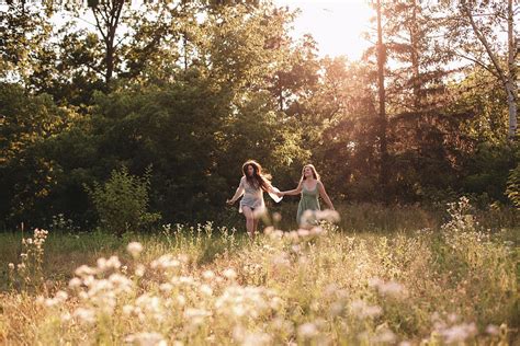 Happy Lesbian Couple Holding Hands While Running In Forest In Summer