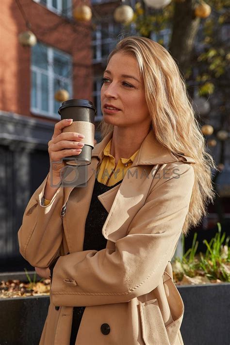 Caucasian Attractive Woman In Beige Trench Coat Holding Cup Of Coffee