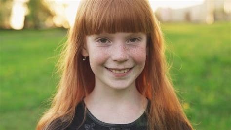 little beautiful redhead girl with freckles smiling and looking at