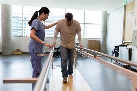 male patient takes first steps using orthopedic parallel bars midwest