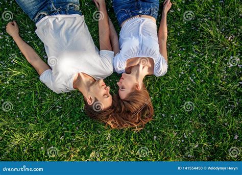 Romantic Couple Of Young People Lying On Grass In Park They Lay On The