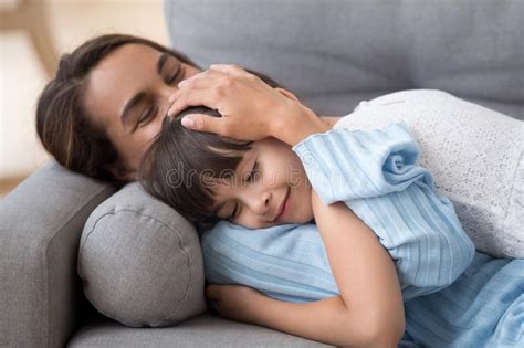 loving mother caressing cute little daughter lying on sofa toget stock