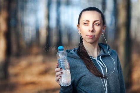 Woman Holding A Bottle Of Cold Water In Her Hand Outdoors In The Park