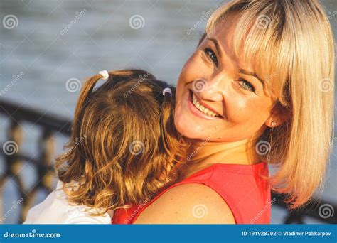 beautiful blonde mom in a red t shirt with her daughter close up stock