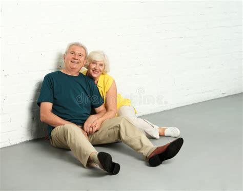 Happy Mature Couple Sitting On Floor Near Wall In Their New House Stock