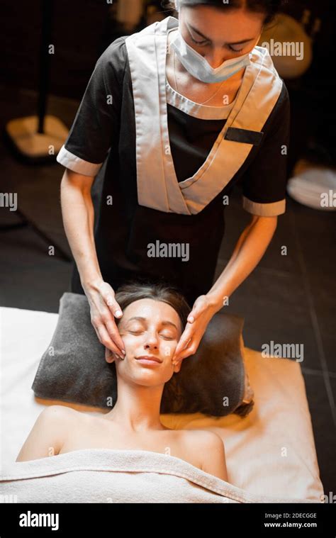 Young Woman Receiving A Facial Massage Relaxing At Spa Salon Stock
