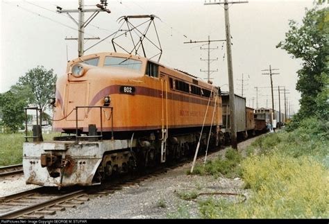 orange train traveling  tracks   power lines