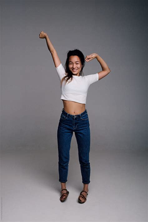 happy asian woman with naked tummy stretching arms by stocksy
