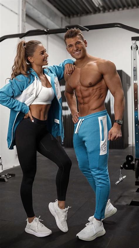 A Man And Woman Standing Next To Each Other In Front Of A Gym Equipment