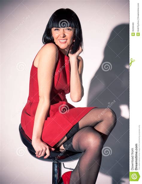 Woman In Red Dress And Stockings Sitting On Bar Chair