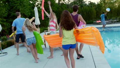 teen friends have a fun chicken fight at a pool party girls cheer them on in the background