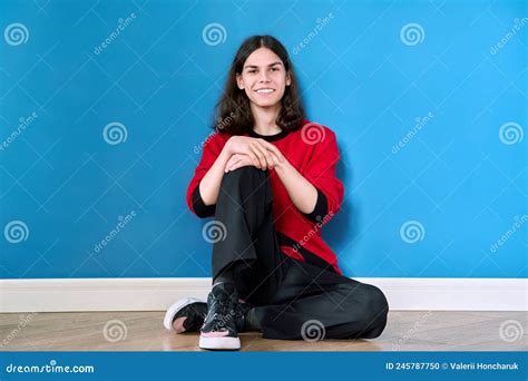 Retrato De Un Joven Adolescente Sentado En El Suelo Sobre Fondo Azul