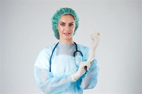 Female Doctor Surgeon In Scrubs With Medical Hat Putting