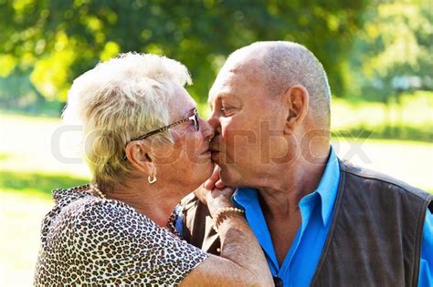 mature couple in love kissing seniors outdoors stock