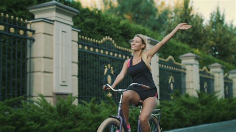 happy woman cycling bicycle in city park fit girl training on bike at
