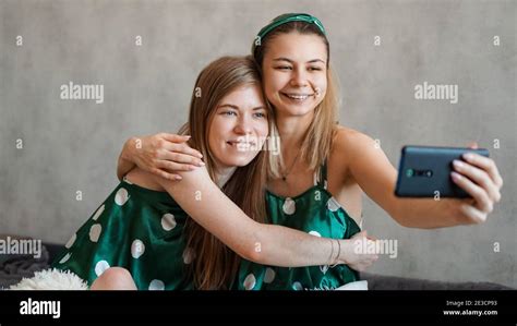 two beautiful happy girlfriends hugging and taking selfies with