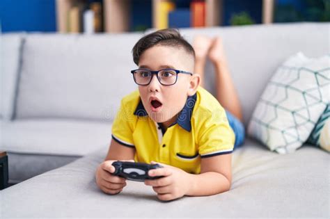 jeune enfant hispanique jouant à un jeu vidéo tenant contrôleur sur le