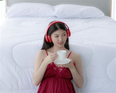 Beautiful Asian Girl Wearing Red Pajamas Sitting In The White Bedroom
