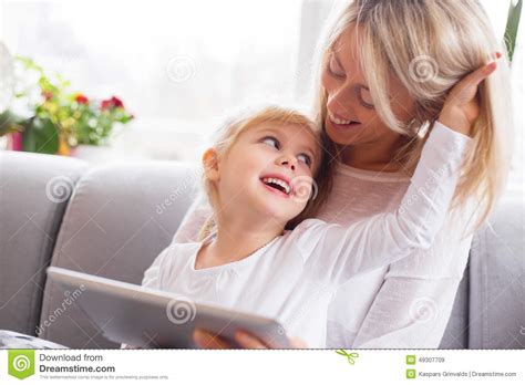 mother and daughter using tablet computer together stock