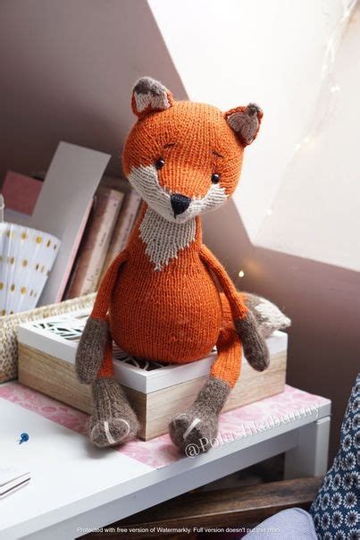 An Orange Knitted Fox Sitting On Top Of A White Table Next To A Wooden Box